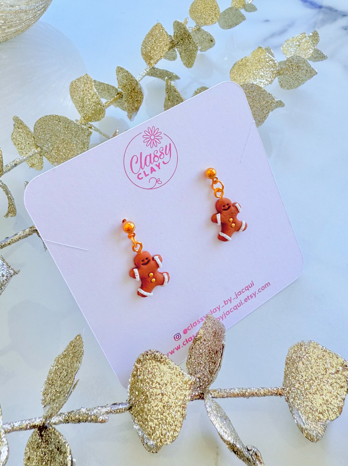 Pair of gingerbread man-shaped earrings on a 'Classy Clay' branded card with decorative elements.