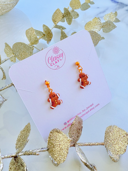 Pair of gingerbread man-shaped earrings on a 'Classy Clay' branded card with decorative elements.