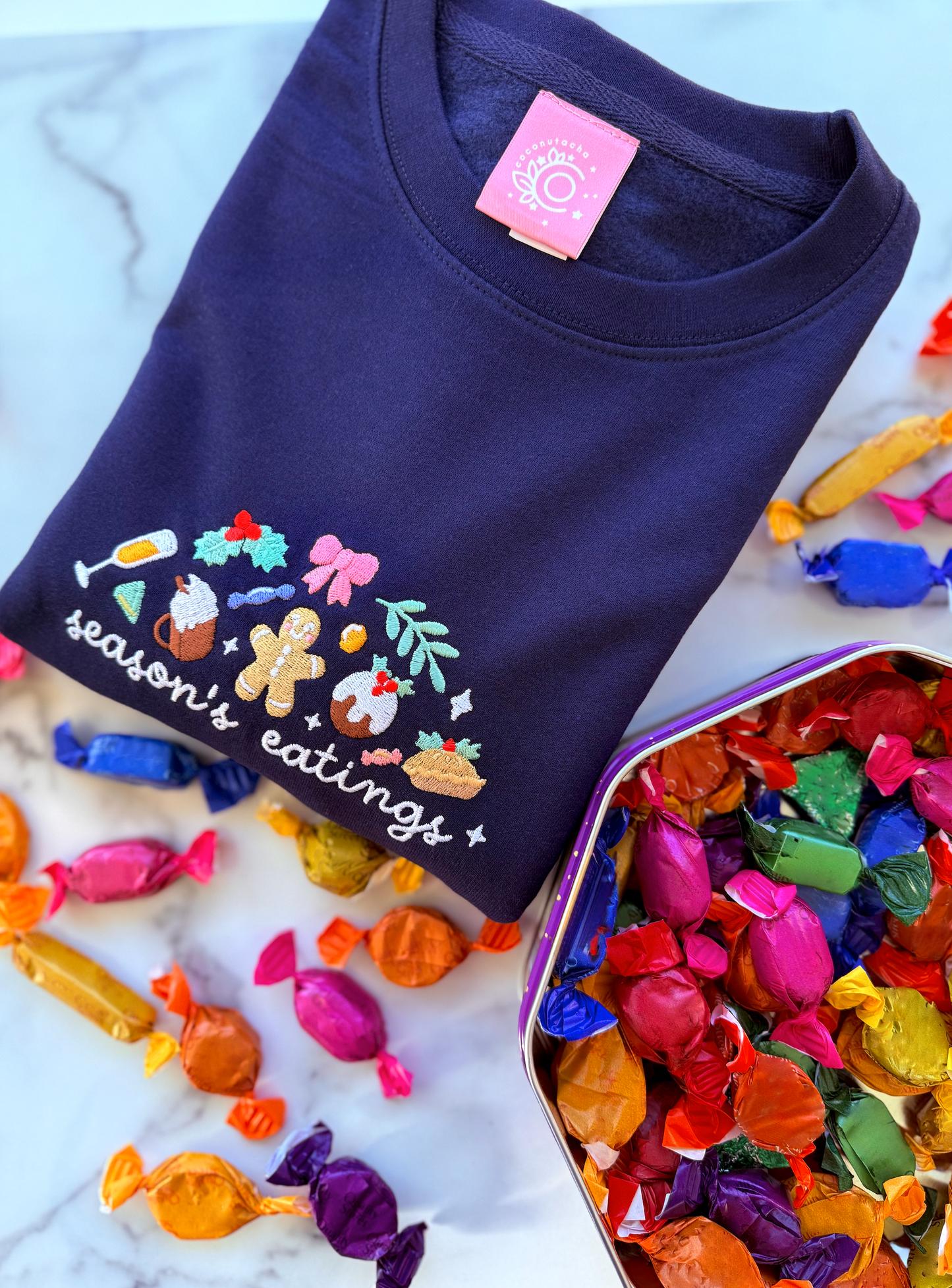 Navy blue t-shirt with colorful embroidered design on a white surface with candy.