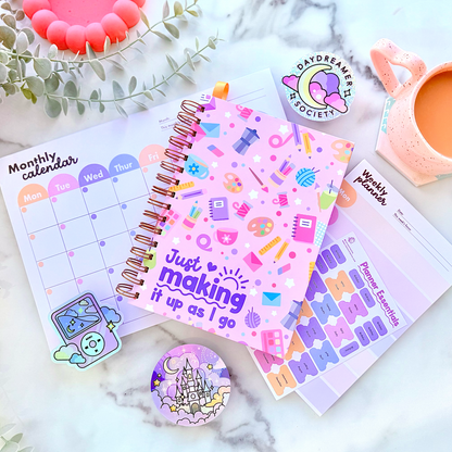 Colorful planner with stickers and decorative items on a marble surface