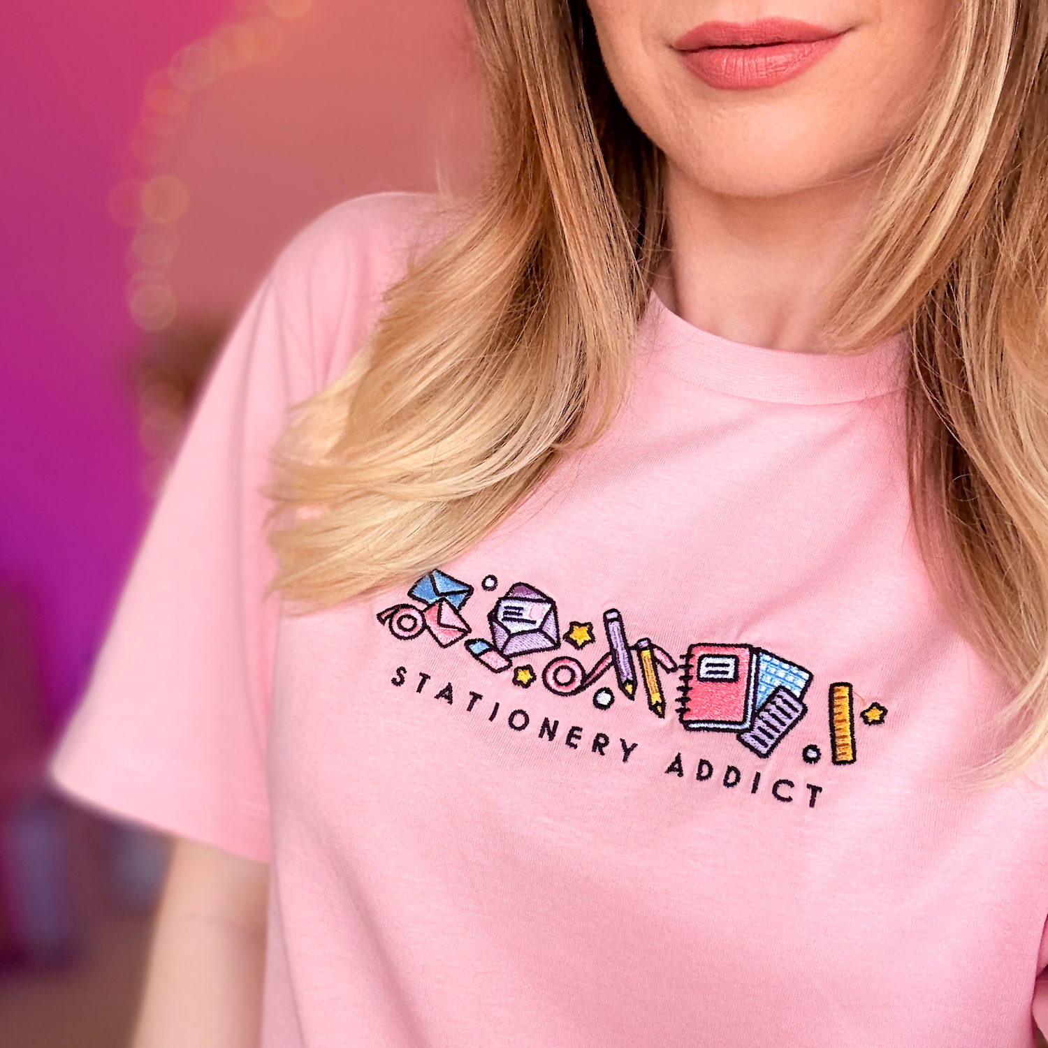Person wearing a pink t-shirt with 'Stationery Addict' design and stationery icons.
