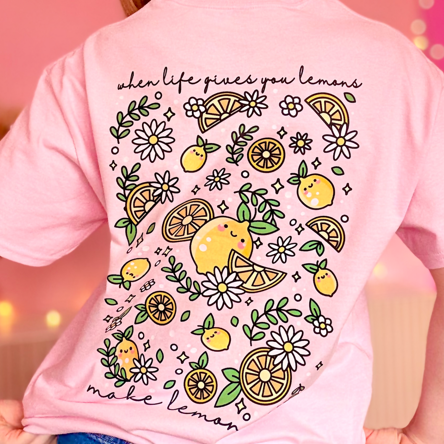 Pink t-shirt with lemon and flower design on the back, worn by a person.