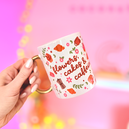 Hand holding a mug with floral design and text against a pink background